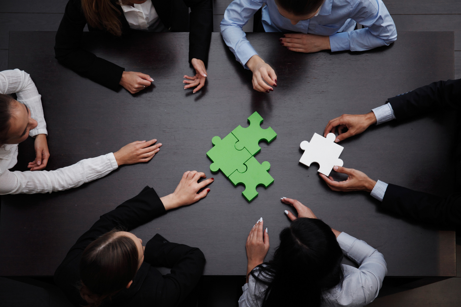 Team collaborating with puzzle pieces at a meeting table